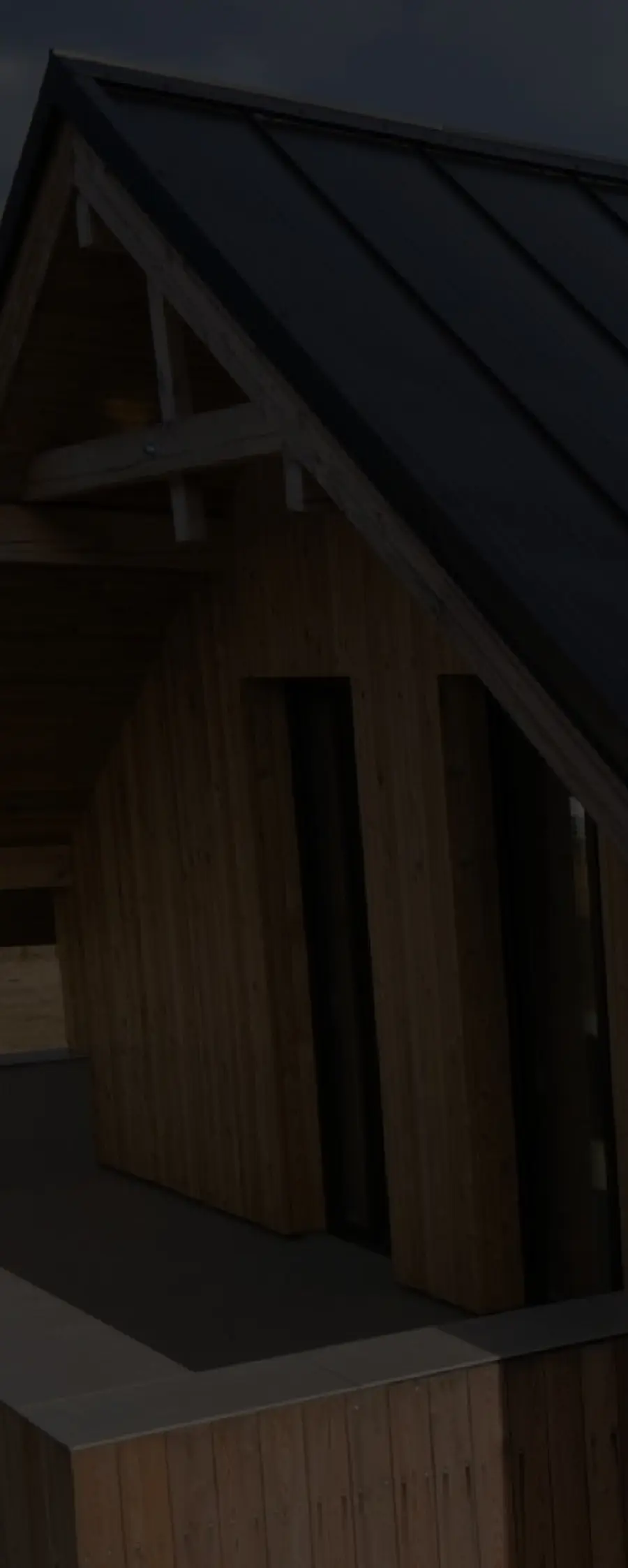 A dark standing-seam metal roof over a timber-clad gable, seen from below.
